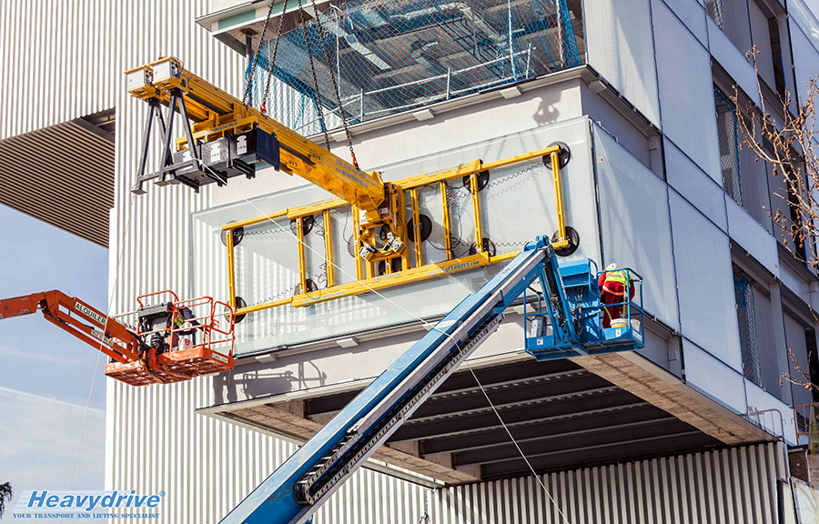 Heavydrive devices and operators during the assembly of a panoramic pane into the glass box facing the sports grounds