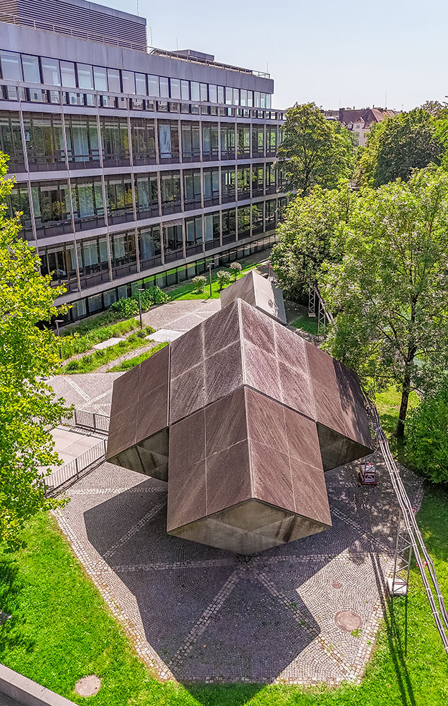 In the background, the completed building complex at Tucherpark in Munich, featuring installed granite and glass facade elements